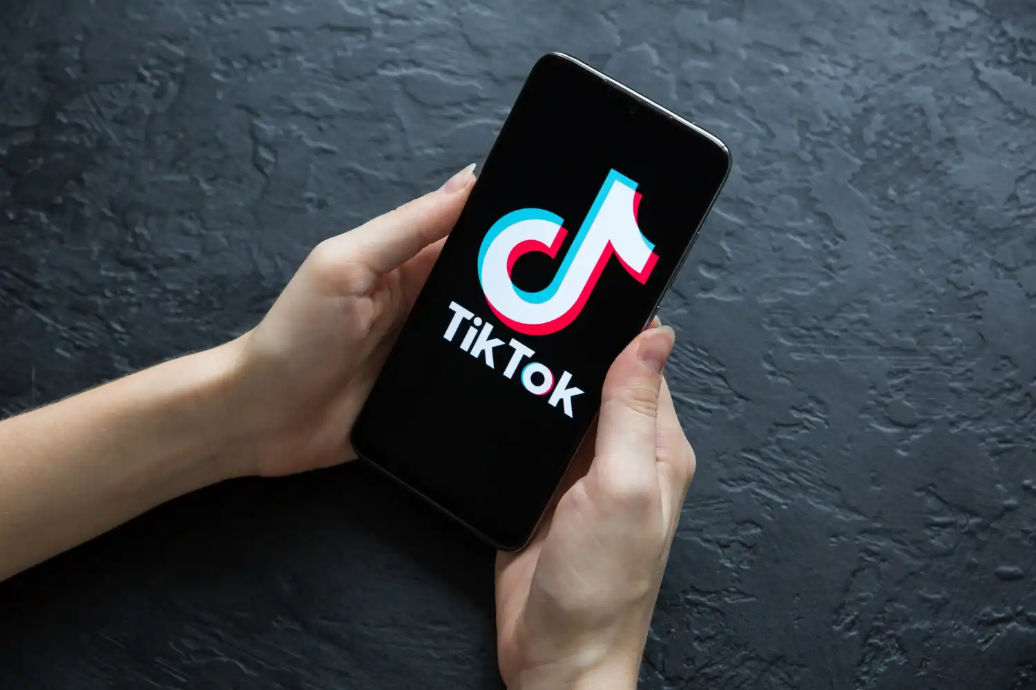 Pessoa segurando um smartphone com o logo do TikTok na tela, indicando a importância da plataforma para empresas e seu potencial no marketing digital.
