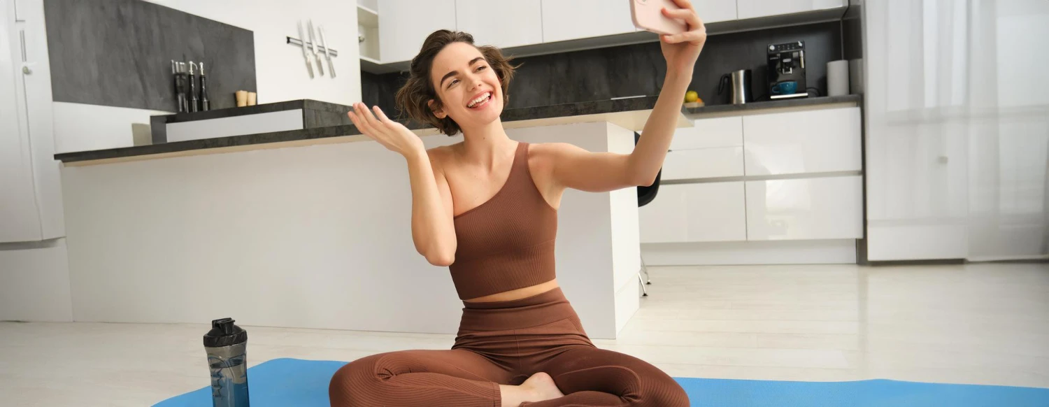 Mulher sorridente praticando alongamento no tapete de yoga na sala, com postura relaxada e braços abertos, inspirando Hábitos simples que podem melhorar sua qualidade de vida no dia a dia.